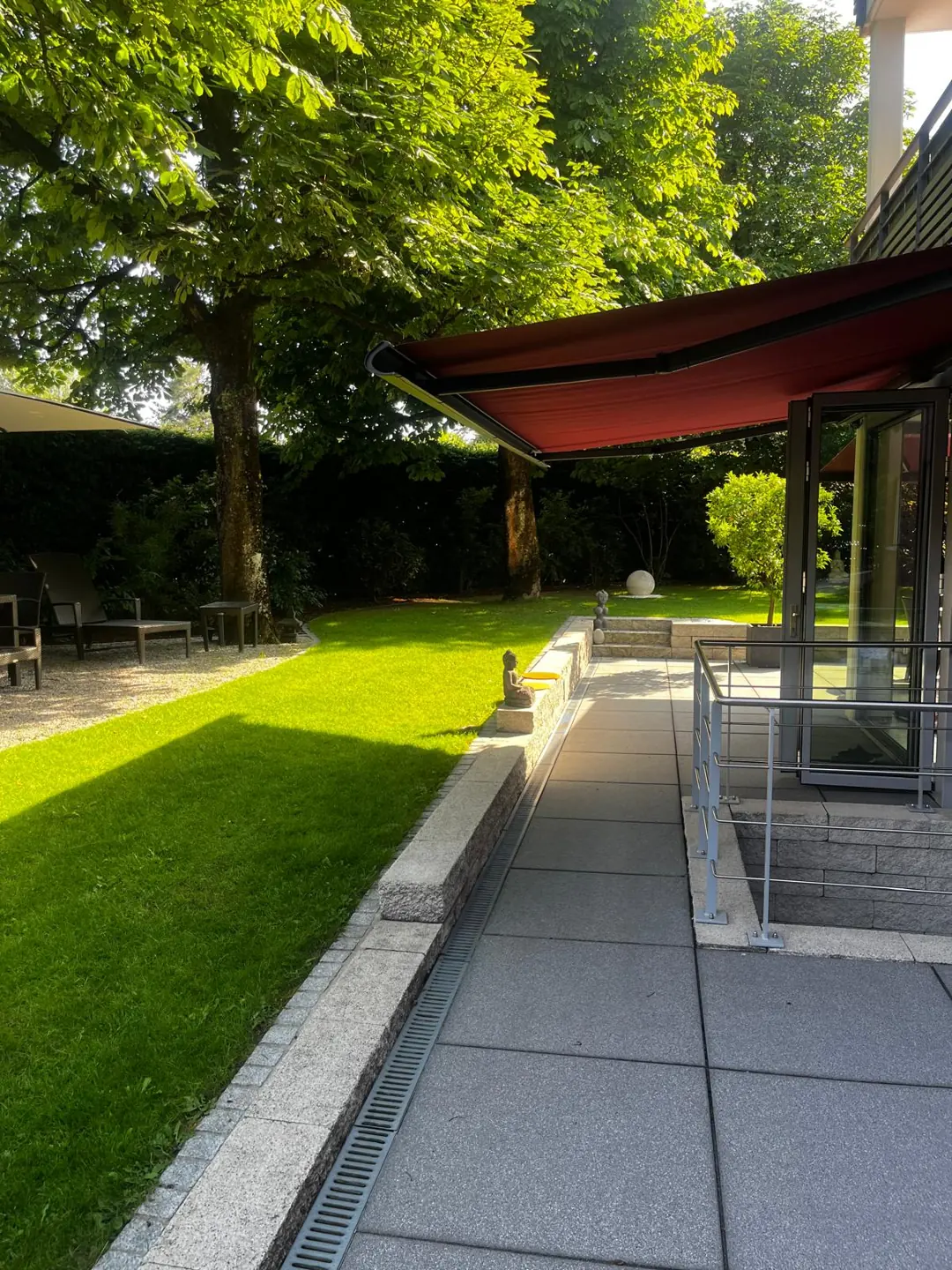 Grüner Garten mit Terrasse und beschattetem Sitzplatz